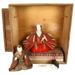A pine box containing a Japanese costume doll on stand, a doll's head, and another dressed doll, box