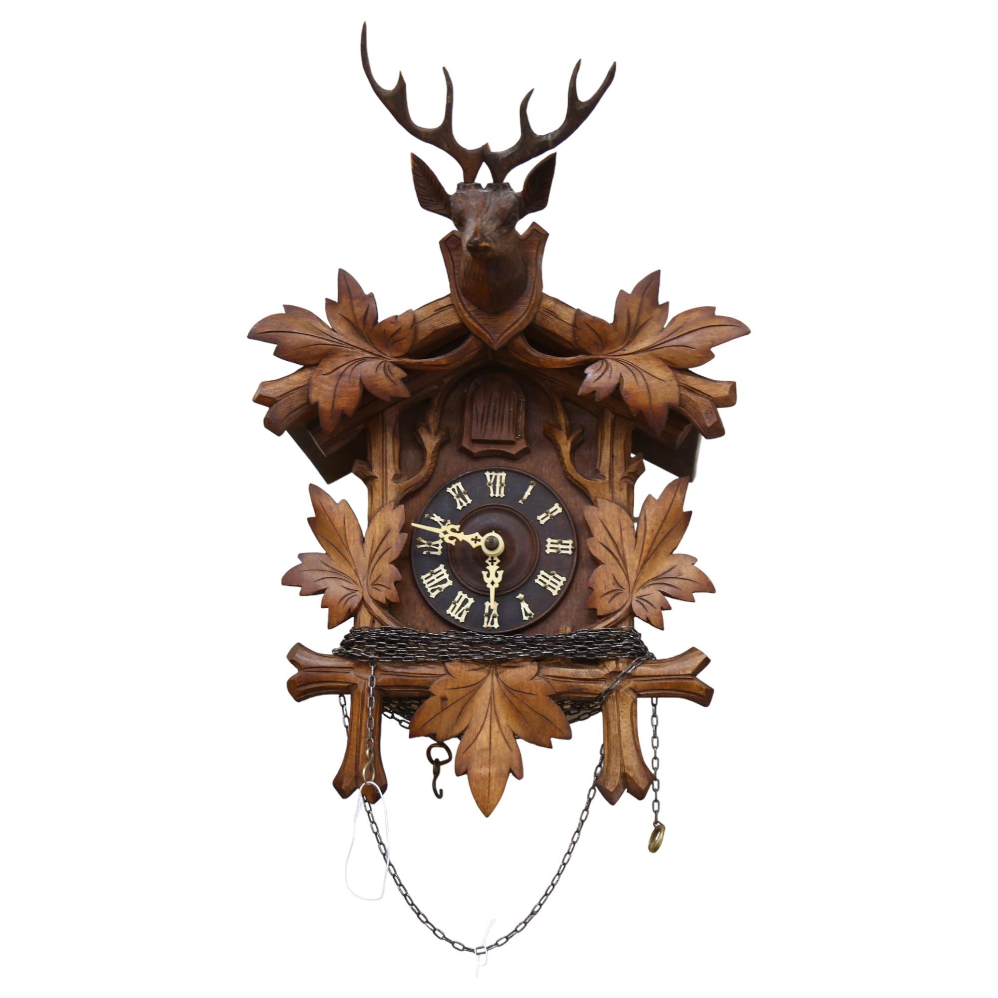 A Black Forest carved cased cuckoo clock, complete with cone weights and pendulum, clock height 50cm