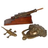 A brass table cannon with ramrod, a brass lizard, and a cast-brass door knocker (Medussa)