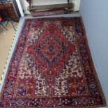 A red-ground Persian Heriz carpet. 330x228cm Some areas of low pile. Nibbles along sides. Some
