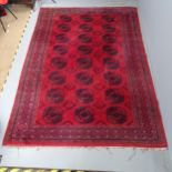 A red-ground Bokhara carpet. 308x220cm. Areas of pile loss and fading. Some damage to fringe.