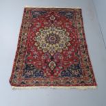 A red-ground Persian Sarouk rug. 202x138cm Repair at centre of rug. Some areas of pile loss and