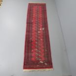 A red-ground Bokhara runner. 280x80cm. Several damaged areas with severe pile loss. Faded.