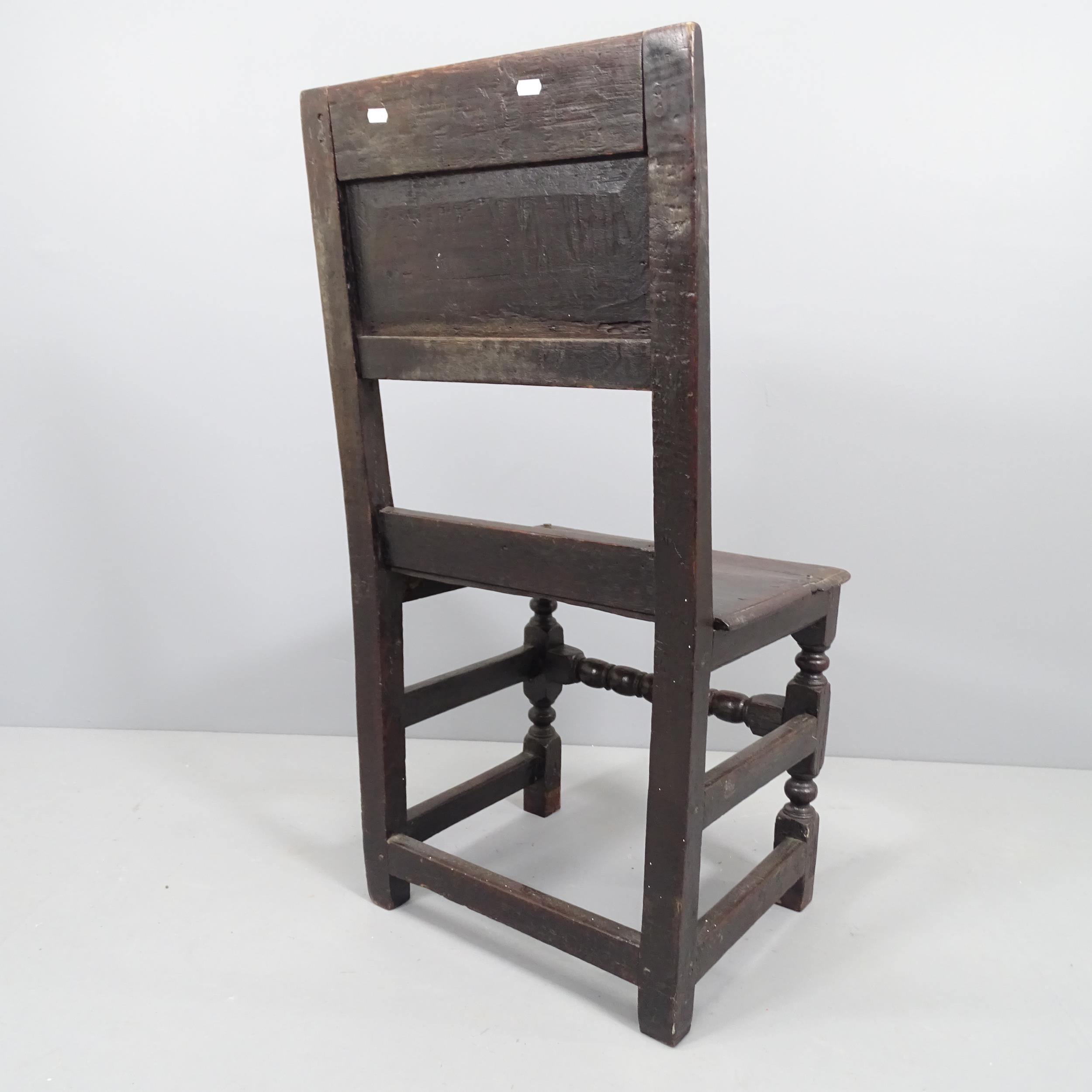 A 17th century and later panelled oak hall chair with carved back and turned stretcher. - Image 2 of 2