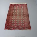 A red-ground Afghan Buchara rug. 174x110cm Very faded. Fringe to only one end. Some nibbles to