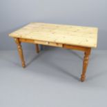 A modern pine farmhouse kitchen table, with single drawer and raised on turned legs. 140x75x80cm