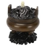 A Chinese patinated bronze censer, of circular form with loop handles, the carved and pierced wooden