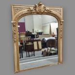 A large 19th century ornate carved giltwood framed wall mirror, with carved and scrolled shield