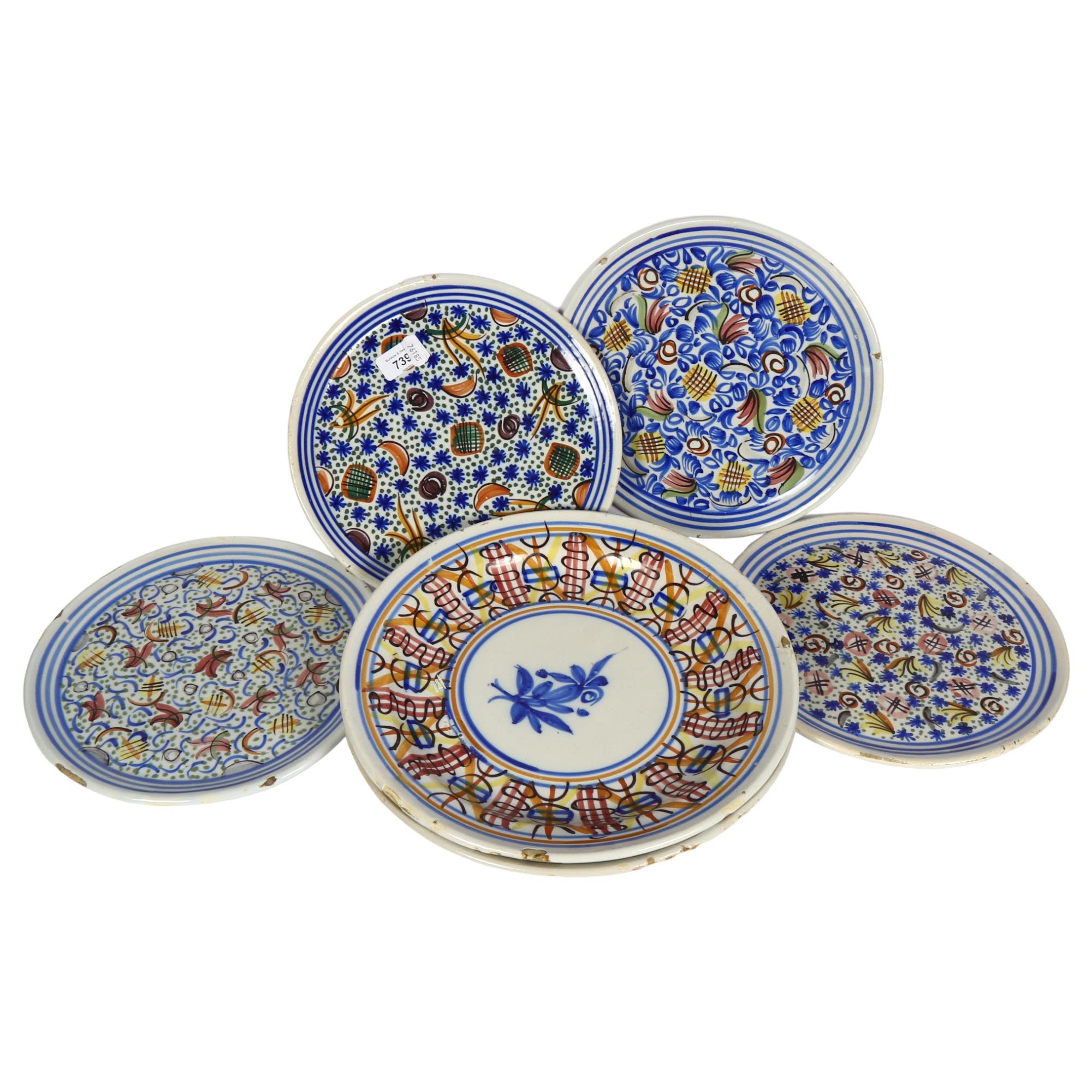 A set of 4 tin glazed earthenware plates with painted decoration, 26.5cm, and 2 larger shallow