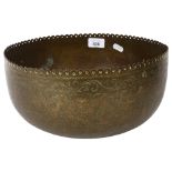 A Tibetan engraved brass singing bowl with design of figures and foliage, and shaped pierced rim,