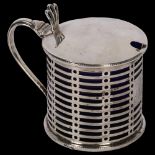 A George V silver drum-shape mustard pot, with pierced decoration and blue glass liner, London 1912,