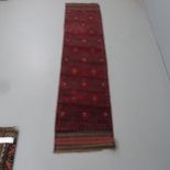 A red ground Meshwani runner. 252x57cm.