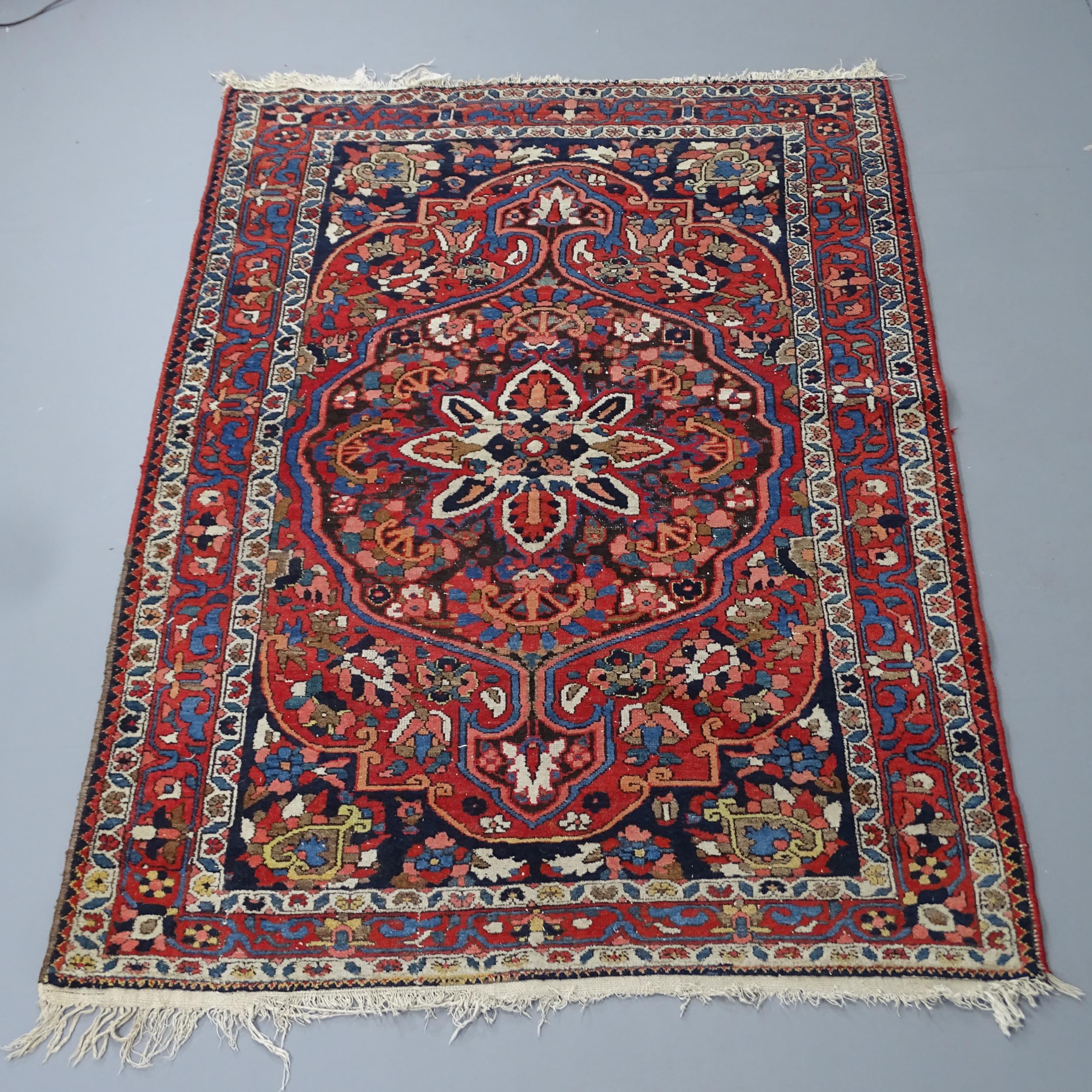 A red-ground Sarouk rug. 200x136cm Some damage to fringe, otherwise good condition.