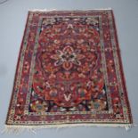 A red-ground Sarouk rug. 200x136cm Some damage to fringe, otherwise good condition.