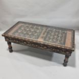 An ornate Moroccan centre table, made from an Antique studded and metal inlaid door behind a glass