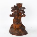 A German Black Forest carved figural candlestick, depicting boy picking fruit from a tree, height