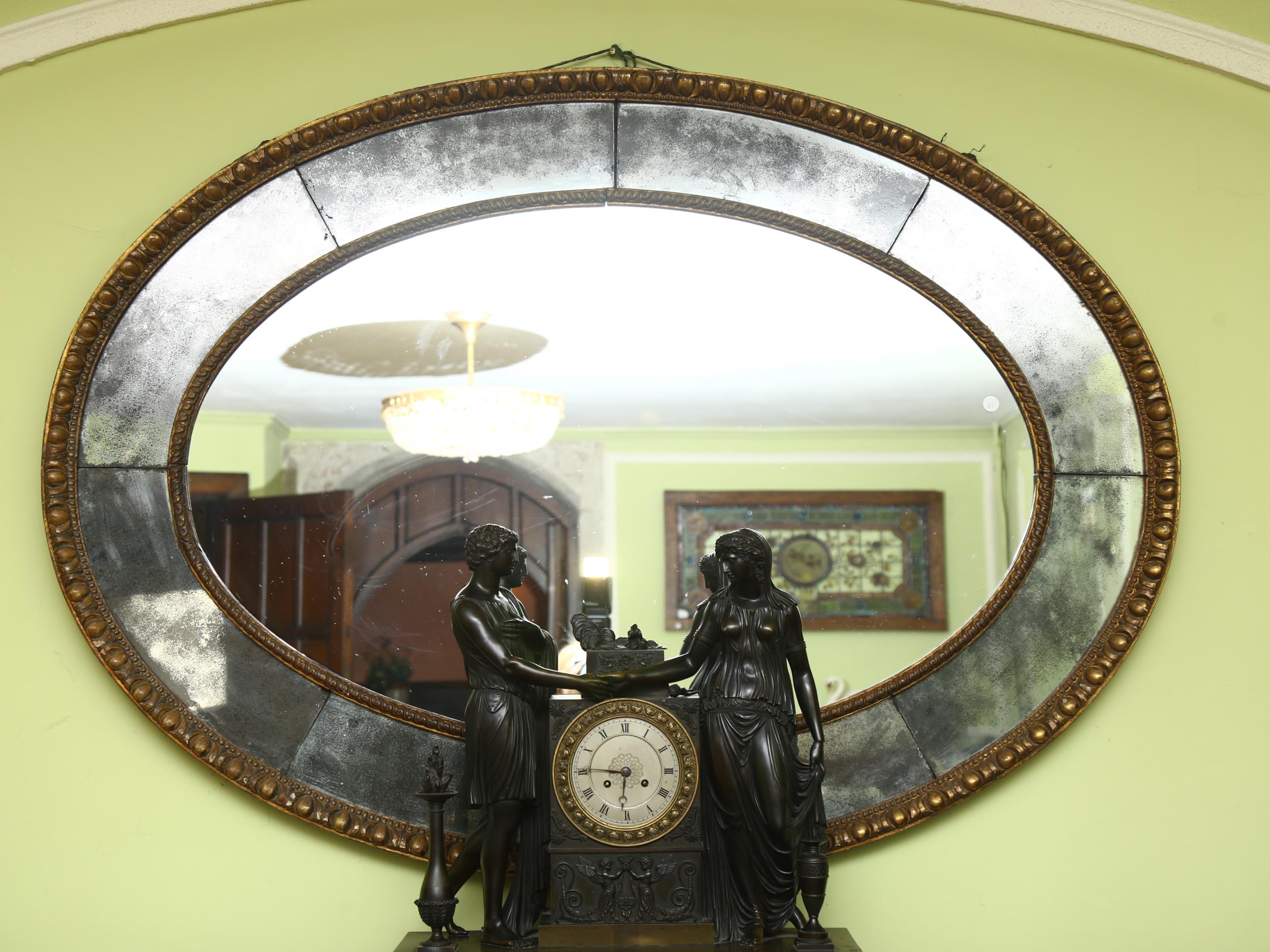 A large oval gilt-framed wall mirror, with inset oxidised mirrored surround, overall measurements