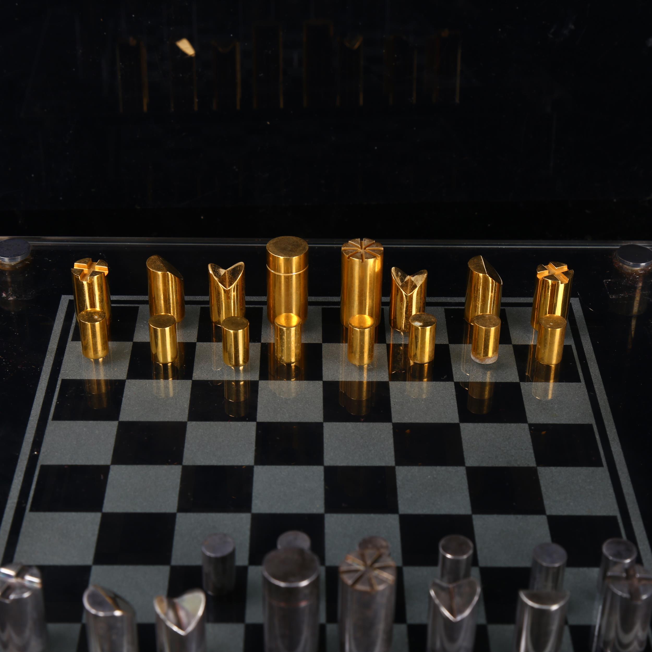 A Modernist hand turned steel and brass chess set, with glass chess board in original leather - Bild 3 aus 3
