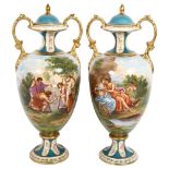 A pair of early 20th century Continental urns and covers, with transfer printed panels and gilded