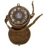 A Tibetan white metal travelling gau box of circular form, the front embossed with Buddhist emblems,