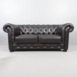 A two-seater black button-back leather upholstered Chesterfield style sofa. Overall 188x80x90cm.