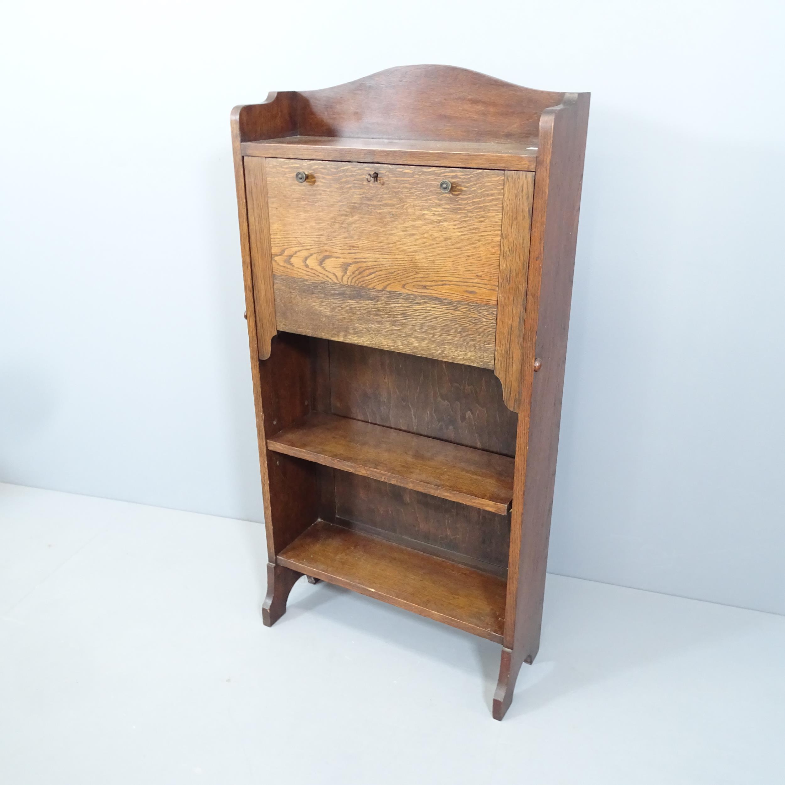 A 1920s oak student's bureau, the fall front revealing a fitted interior with shelves beneath.