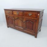An antique oak sideboard, possibly by Titchmarsh and Godwin, with three drawers and cupboards under.