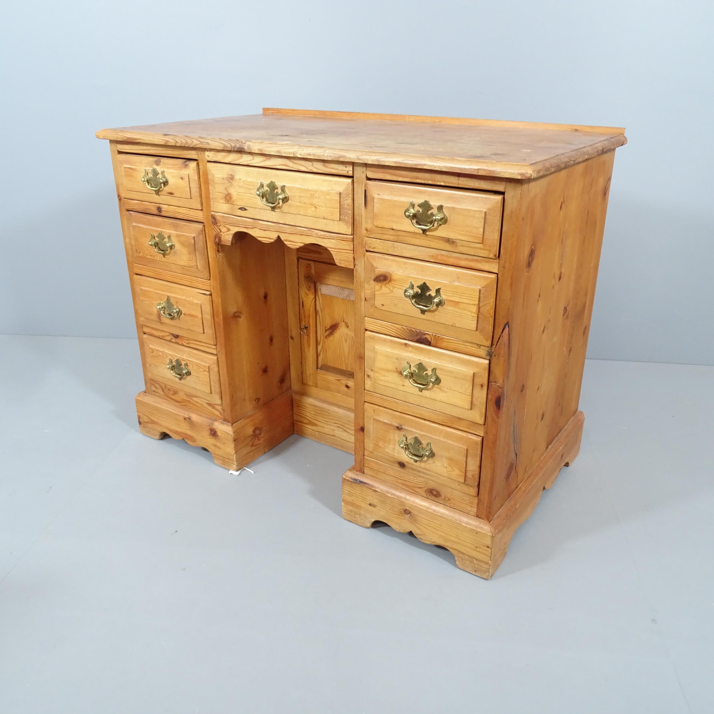 A modern pine kneehole desk, with nine drawers and recessed cupboard. Overall 101x78x56cm,
