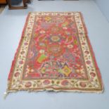 A red-ground Persian style wool rug with floral decorated medallion. 210x125cm.