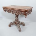 A 19th century carved oak fold-over card table, raised on central column with platform base.
