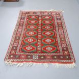 A red-ground wool rug with Afghan design. 155x110cm.