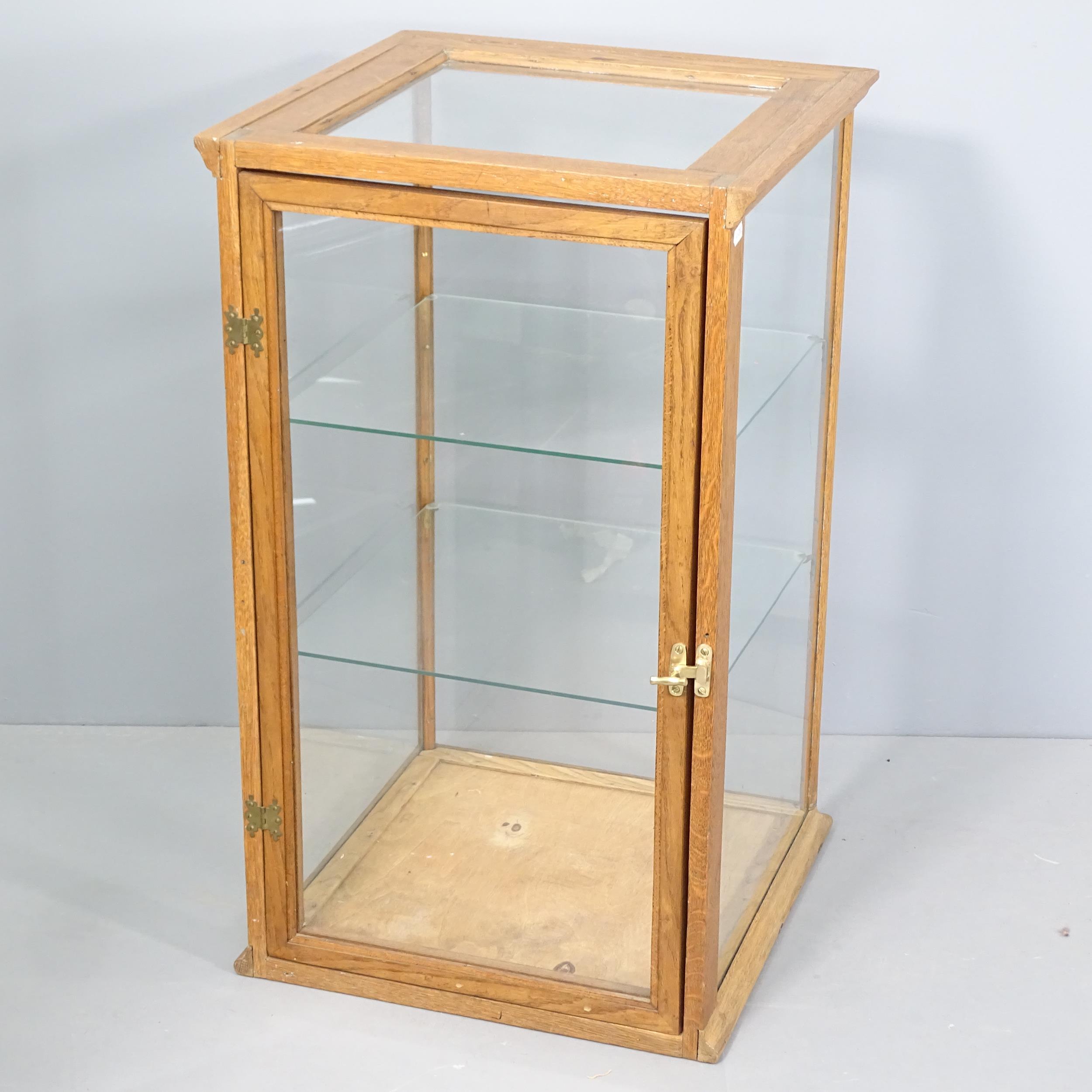 An early 20th century oak framed and glazed shop display cabinet with two glass shelves. 46x76x46cm.