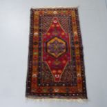 A handmade Persian red-ground rug. 130x72cm.