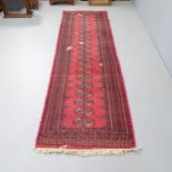 A red-ground Bokhara runner. 280x80cm Several damaged areas with severe pile loss. Faded.