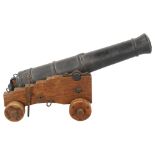 A Victorian iron table cannon on wheeled wooden carriage base, barrel length 39cm