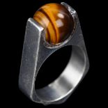 A mid-20th century Danish modernist sterling silver tigers eye orb ring, with angular shank,