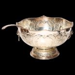 A large silver plate on copper punch bowl and ladle, with repousse decoration and lion mask ring