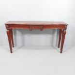 An antique mahogany console table of serpentine front, with carved decoration and raised on square