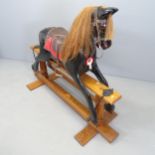 A vintage black painted rocking horse with glass eyes on mahogany base, with label for 'G M Mayes,