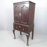 A 19th century two-section cabinet on stand, with two panelled doors revealing a shelved interior,