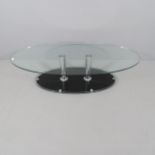 A contemporary oval glass top coffee table, on chrome supports with platform base. 135x34x65cm.