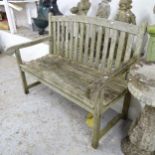 A weathered teak slatted garden bench, with label for Firman Leisure. 121x94x65cm.