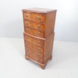 A reproduction mahogany bedside chest-on-chest in one section, with seven drawers and bracket