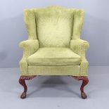 A mahogany and upholstered Queen Anne style wingback armchair, on cabriole legs with claw and ball