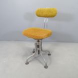 A mid-century industrial machinist's stool with rise and fall mechanism and adjustable backrest.