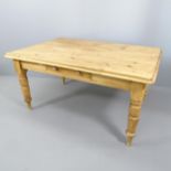 An antique pine farmhouse kitchen table, with single frieze drawer and raised on turned legs.