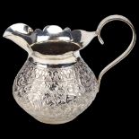 An Indian silver cream jug, squat ovoid form with allover floral embossed decoration, height 7cm,