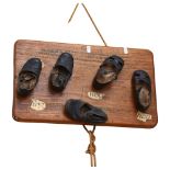 A Folk Art sculpture, a group of 5 Antique children's shoes attached to a wooden board, with Roman