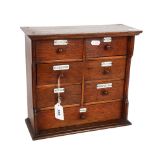 An early 20th century oak table-top chest of 7 drawers, with aluminium name plates, including