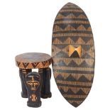 A Ugandan carved stool, diameter 22cm, height 26.5cm, and an African shield, L66cm (2)